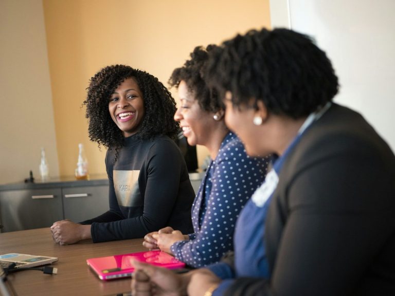 Black woman facilitating a leadership coaching session with two Black nonprofit leaders engaged in a lively discussion at a meeting.