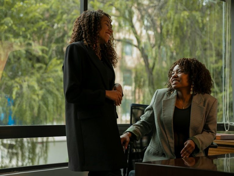 Black facilitator leading an equity-driven strategic planning meeting in professional attire in a bright office with greenery outside.